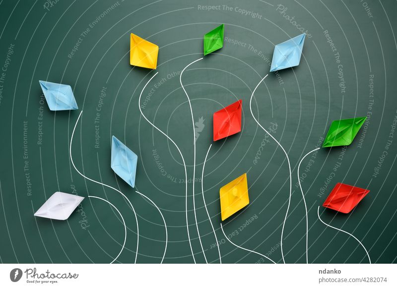 a group of multi-colored paper boats flies in different directions on a green background blue boss business competition concept creative creativity dispute