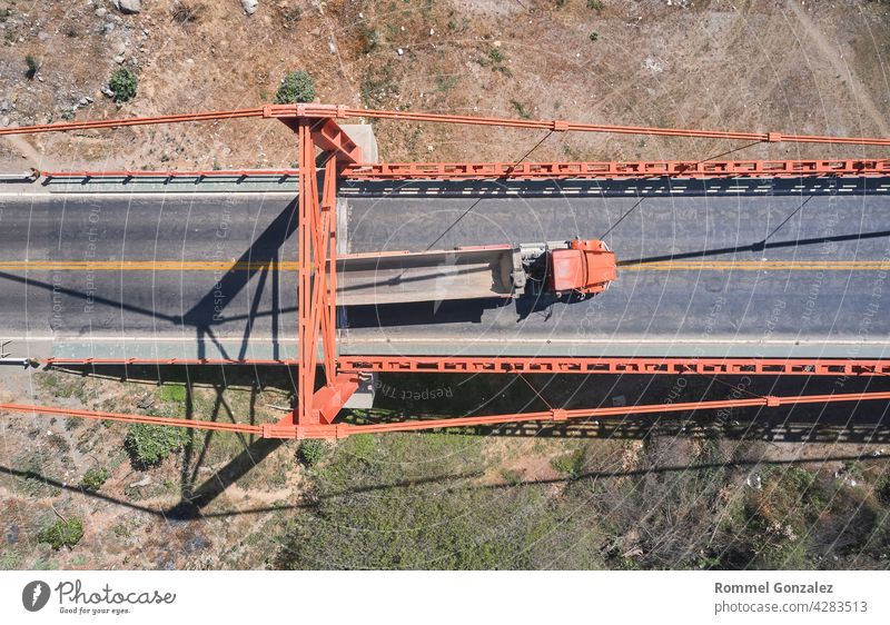 Truck crosses beautiful bridge in summer. Scene. Aerial view of truck carrying things driving across bridge on background expressway nature landscape mountains
