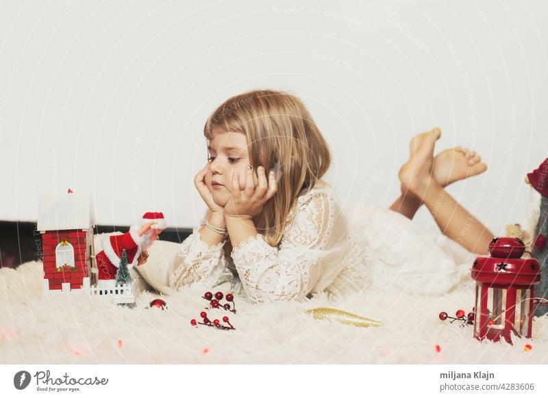 Little girl laying on the floor, playing with Christmas decoration; Christmas background with copy space box card carpet caucasian celebration child childhood