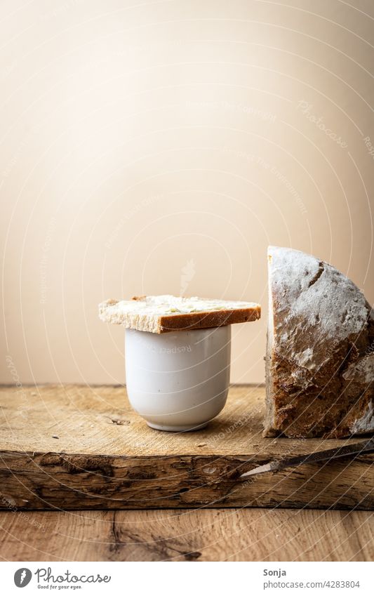 A slice of bread with butter on a coffee cup Coffee Bread Slice Butter Breakfast Wooden table Morning Food Nutrition Rustic Rural beige background Delicious