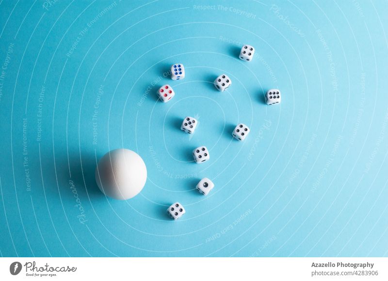 Minimal layout with a white egg and dice on blue background wager tabletop group concept minimalism life arm bet birth bone chance composition game goal hen