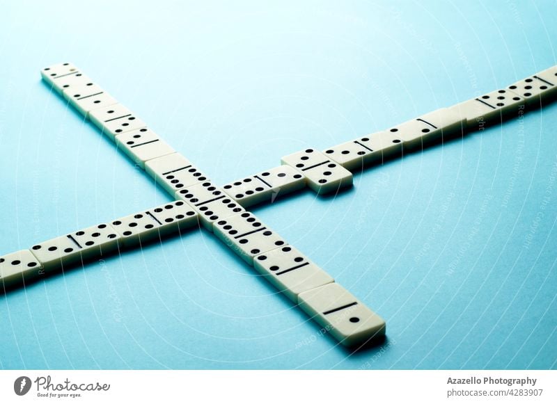 Domino pieces on blue background with an empty space for text copy minimalist symbolic domino bone gambling ivory stone game play think score champion leisure
