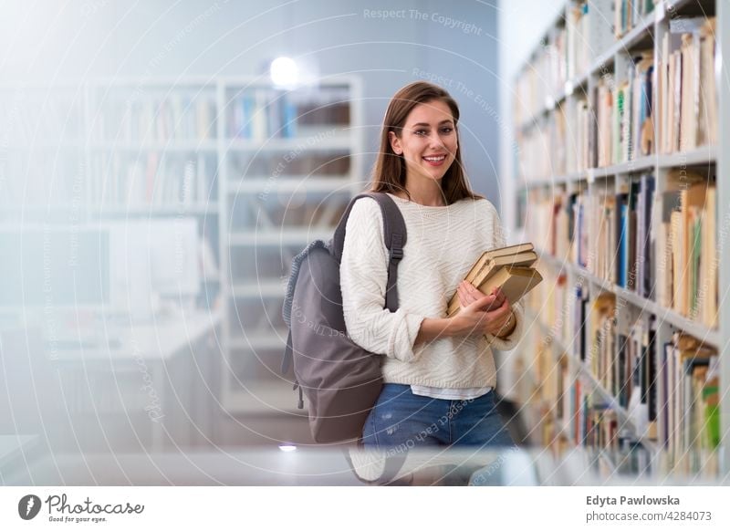 Young female student in a university library enjoying lifestyle young adult people one person casual caucasian positive happy smiling woman attractive beautiful