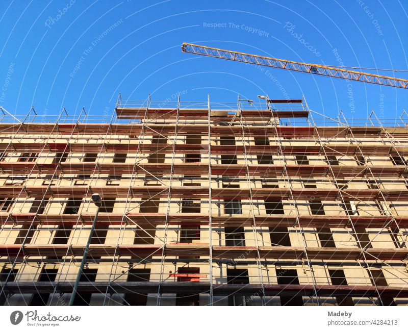 Building complex in shell with scaffolding for the creation of living space in the Rhine-Main area in front of a blue sky with sunshine in Offenbach on the Main in Hesse