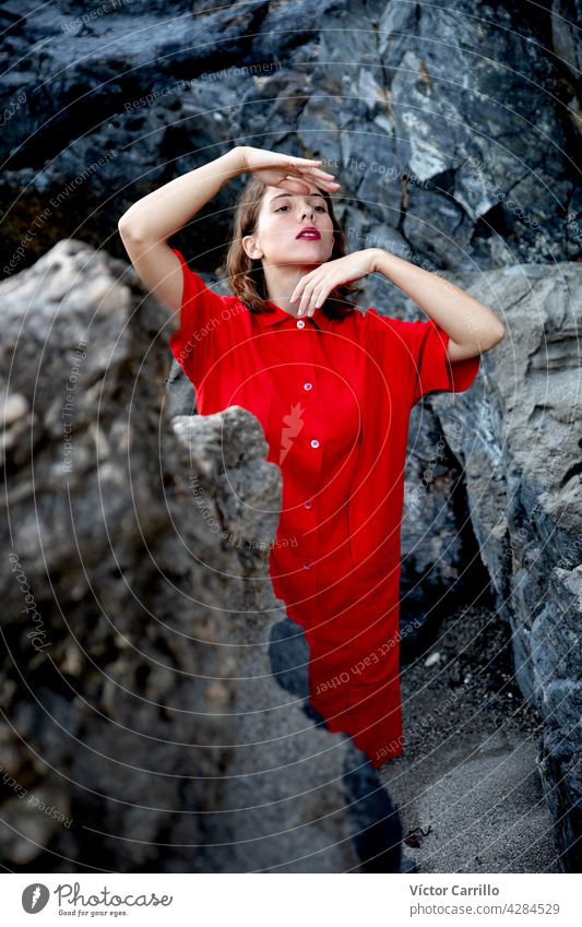An elegant fashionable fresh beautiful woman in a red vintage dress with rocks background. portrait beauty young model hair face person cute wall smiling smile