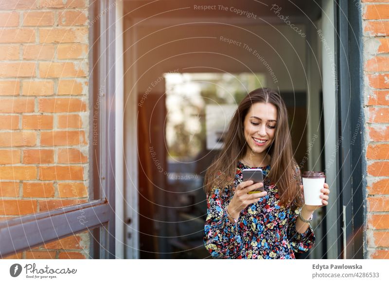 Young woman standing in front of a cafe urban Street City stylish Coffee to go people Woman young adult more adult Easygoing Attractive Smiling Happy Caucasian