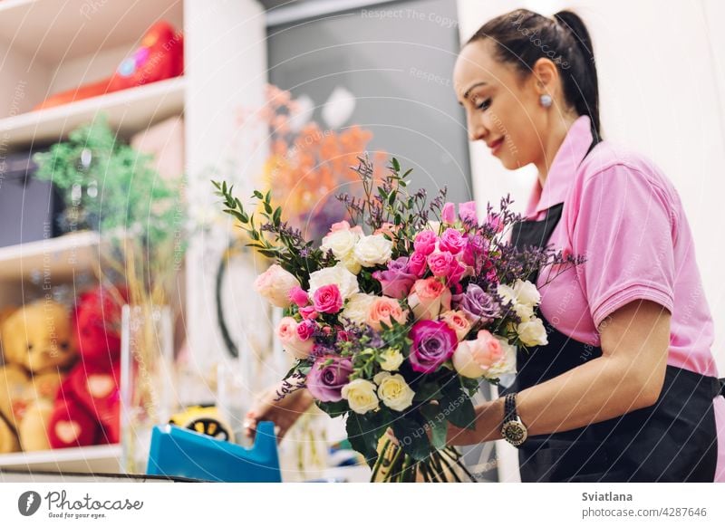 A florist girl in a flower shop makes a bouquet for the holiday. Family flower business, beautiful flower arrangement. flower composition pink roses