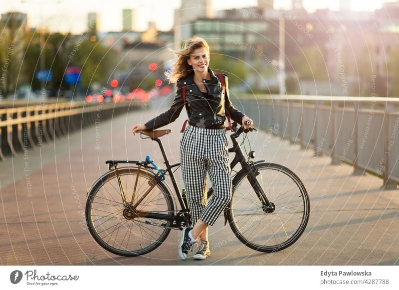 Attractive young woman standing with her bicycle in the city enjoying lifestyle adult people casual caucasian positive happy smiling female attractive beautiful