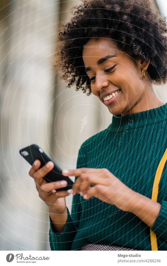 Business woman using her mobile phone outdoors. afro business black modern style brunette gadget positive concept connection application sms texting