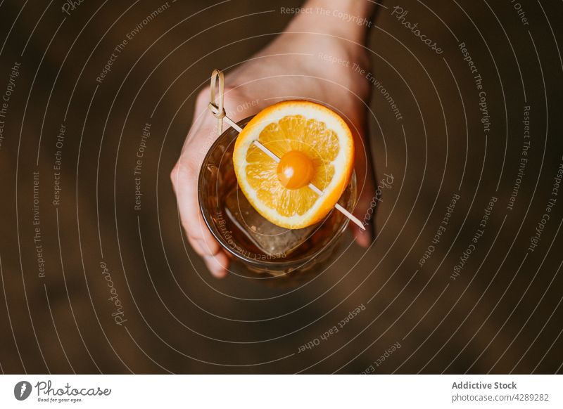 Person with whiskey with ice and piece of orange person alcohol fruit cube berry cold transparent cool crystal liquid stick glassware beverage frozen citrus