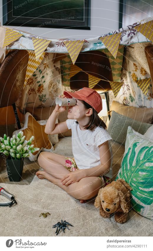 Girl playing with cardboard binoculars while camping at home happy girl observing vacation diy toys tent lockdown smiling coronavirus carton toilet paper tubes