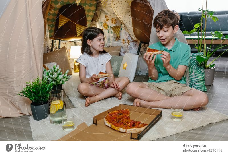 Children eating pizza and lemonade while camping at home children happy tent brother dinner lunch enjoy cheerful cute holiday food fun smiling homemade drink
