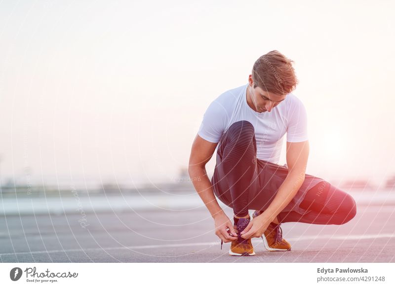 Sporty young man on parking level in the city at sunset Jogger runner jogging running people male energy exercise clothing exercising fitness recreation sport