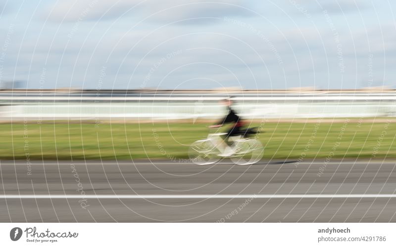 Woman cyclist in motion on a straight asphalt road abstract action active activity adventure Background bicycle bicyclist Bike biker biking blur blurred city