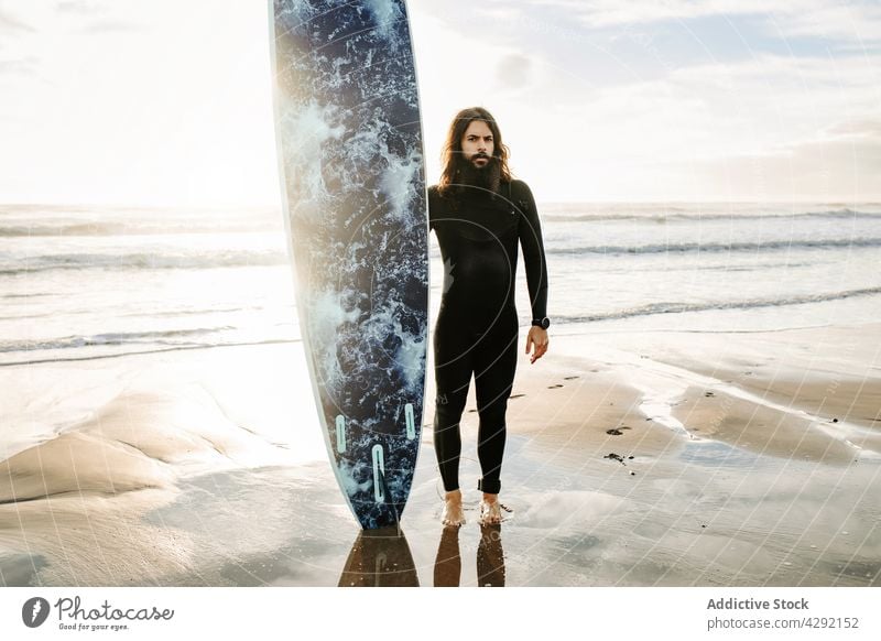 Surfer standing at the beach with surfboard man nature sunset wave outdoors wetsuit seacoast male sportsman beard surfing hobby long hair surfer ocean seaside