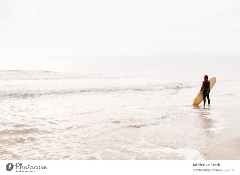 Anonymous surfer at the beach with surfboard man nature stand sunset wave outdoors wetsuit seacoast male sportsman surfing hobby ocean seaside calm catch water