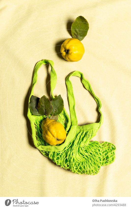 Two quince apple fruits in green mesh bag on linen yellow natural shopping ripe leaf vitamin nature nutrition organic vegetarian quince fruit raw reusable
