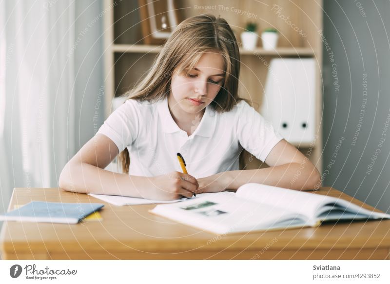 A high school student takes notes from a book, a teenage girl does her homework and prepares for lessons. Education, training, homework write desktop study