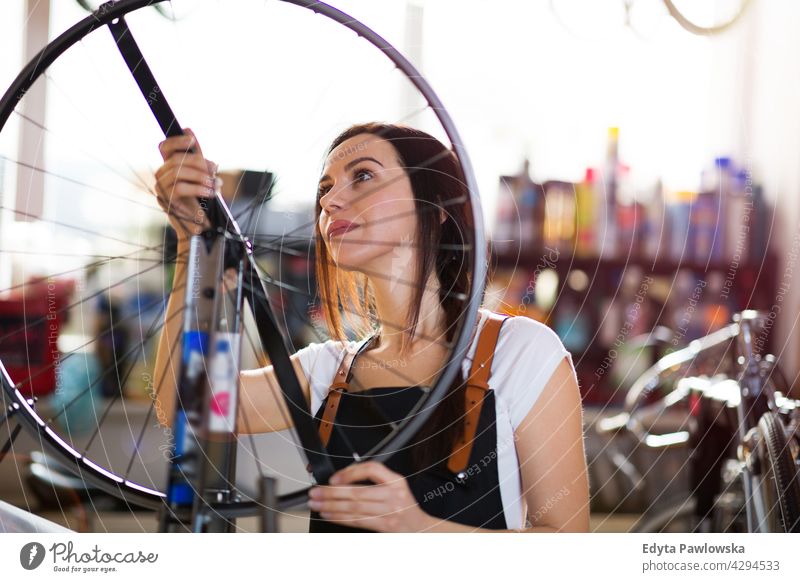 Young woman working in a bicycle workshop Sales Representative Bicycle Bicycle mechanic Cycling bicycle shop Business Retail sector Cycle helpful indoors Woman