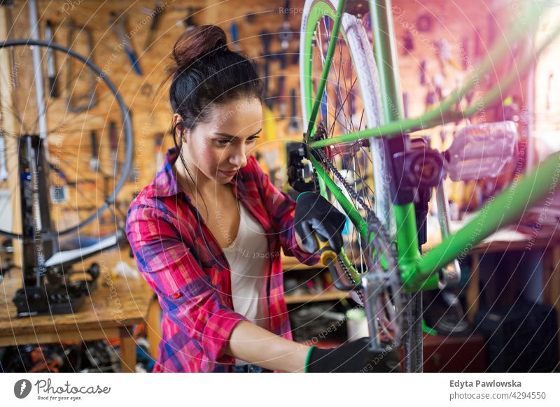 Young woman working in a bicycle repair shop sales clerk bicycle mechanic bicycling bike shop business retail helpful indoors female manager owner profession