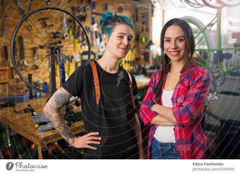 Two young women working in a bicycle repair shop sales clerk bicycle mechanic bicycling bike shop business retail helpful indoors woman female manager owner