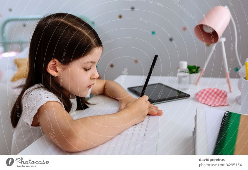 Girl studying at home with mask on table girl writing desk homeschooling school at home coronavirus epidemic disinfectant homework closeup wrong pencil posture