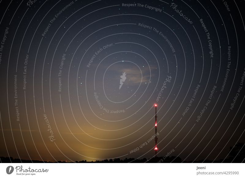 Illuminated radio tower at night | starry sky, light glow and an illuminated city in the distance Transmitting station Tower Antenna radio mast Night Starry sky