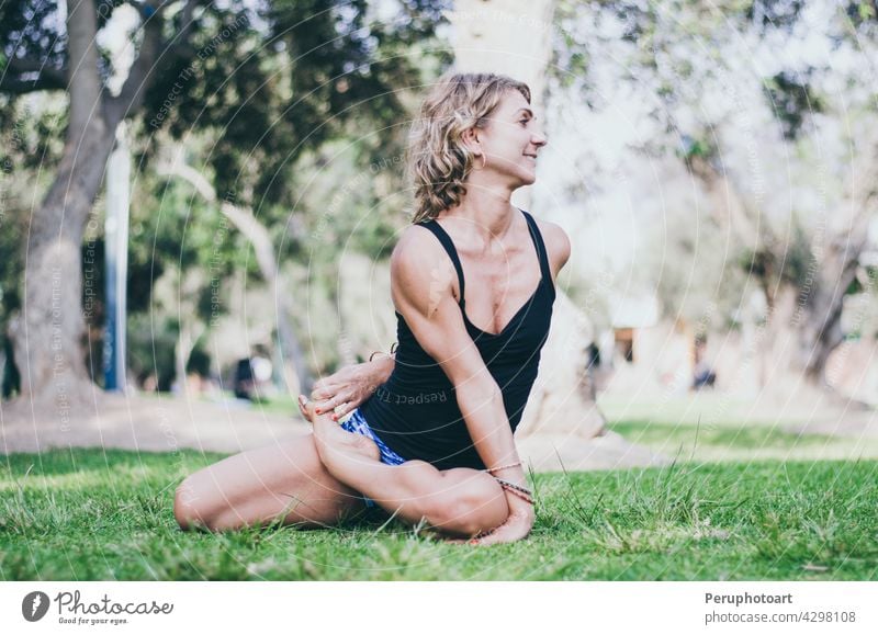 Pretty woman doing yoga exercises in the park. - a Royalty Free