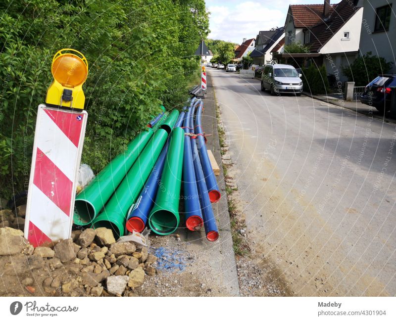 Green and blue plastic pipes at a construction site with a warning beacon in Oerlinghausen near Bielefeld on the Hermannsweg in the Teutoburg Forest in East Westphalia-Lippe