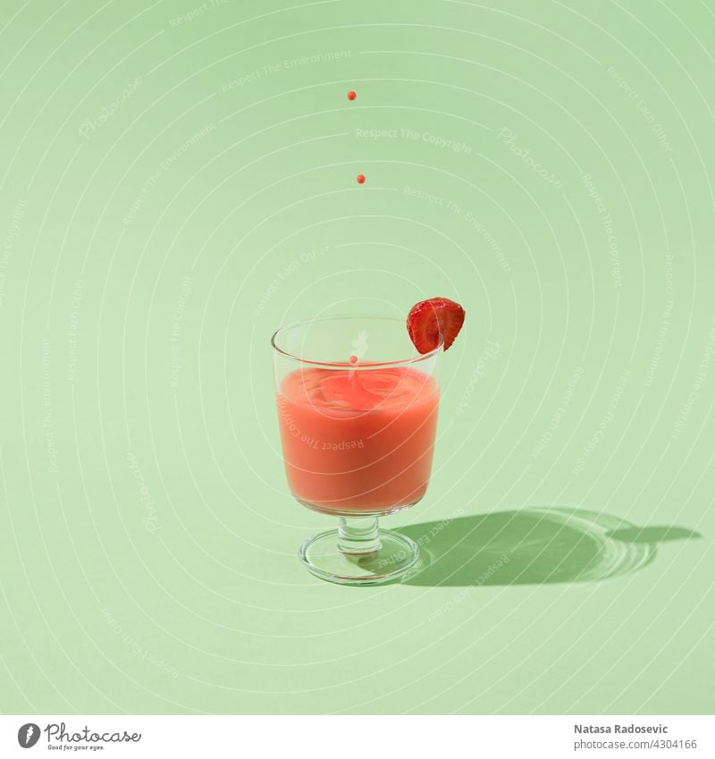 Summer strawberry juice with falling drops isolated on a green background. summer Abstract minimal freshness Contemporary Square aesthetic art beverage cocktail