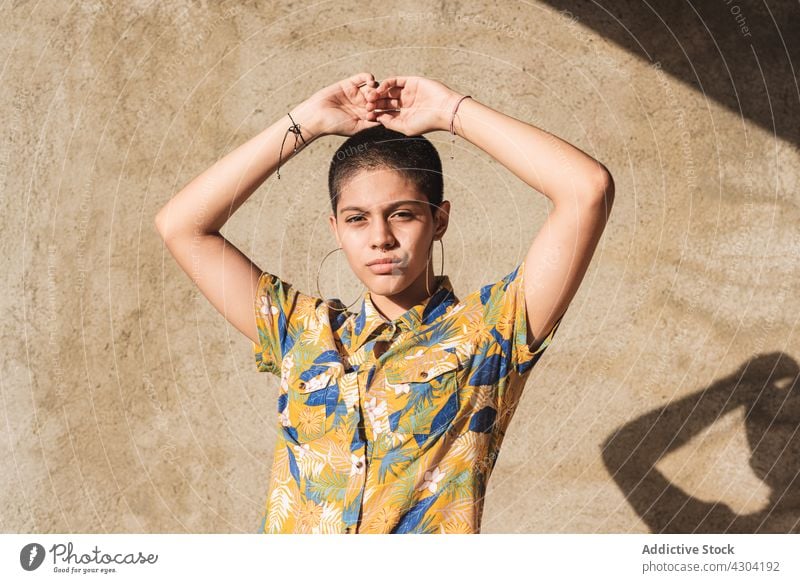 Ethnic woman in shirt with floral ornament in sunlight bisexual gender identity cool individuality vain portrait shadow contemplate contemporary generation