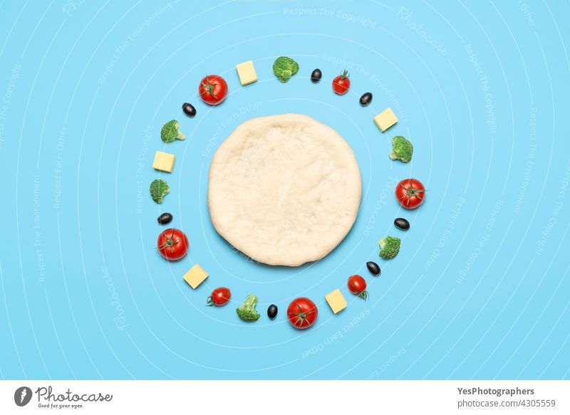 Vegan pizza ingredients, top view. Raw pizza dough and vegetables on blue table above aligned alternative arranged background bake broccoli cashew cheese color