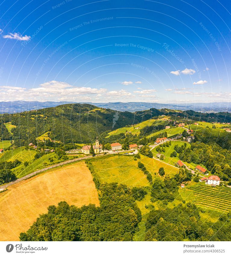 Aerial view of green hills and vineyards with mountains in background. Austria vineyards landscape in Kitzeck im Sausal summer wine nature spring agriculture