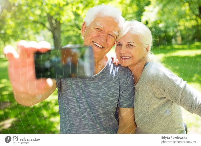 Senior couple taking selfie mobile photo smartphone photographing taking photo taking picture senior seniors pensioner pensioners casual outdoors day Caucasian