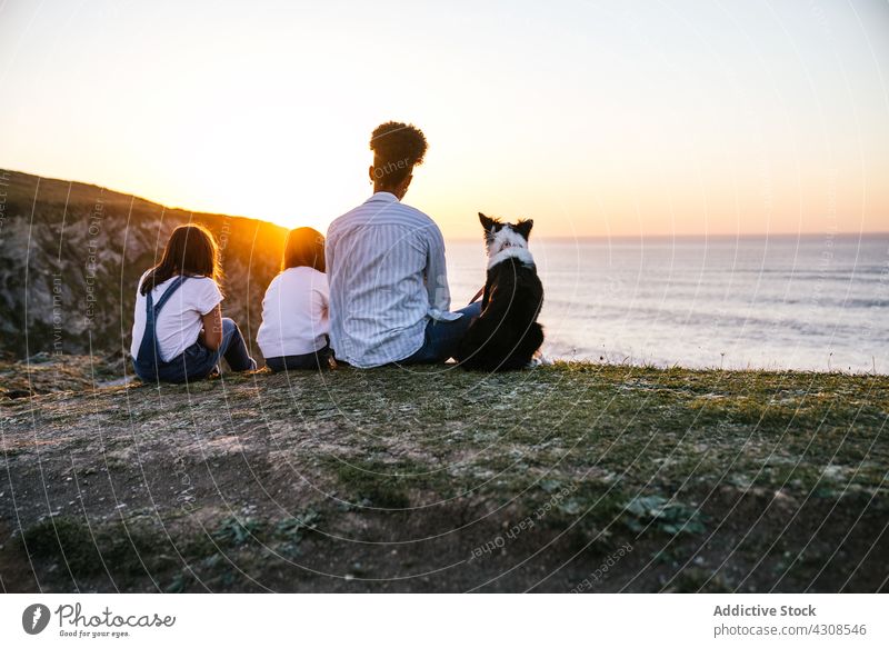 Woman with kids and dog resting on beach at sunset mother together sea pet friend mom children animal shore evening sundown peaceful calm tranquil ocean nature