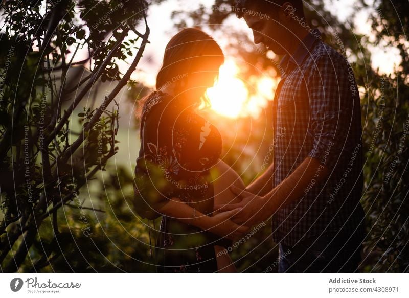 Loving man touching belly of pregnant woman in sunset light couple love together happy nature relationship expect romantic affection pregnancy parent baby