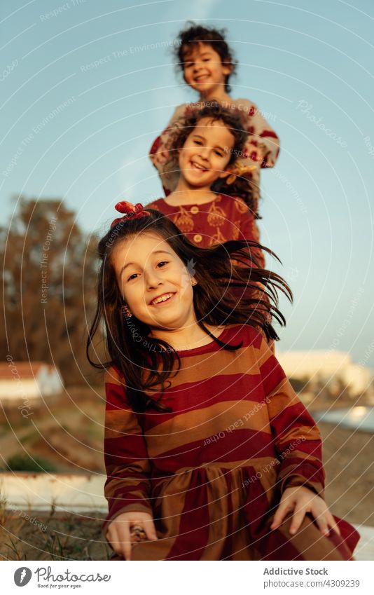 Happy sisters standing behind each other in countryside girl smile rest summer together happy weekend children kid cute cheerful sibling joy casual childhood