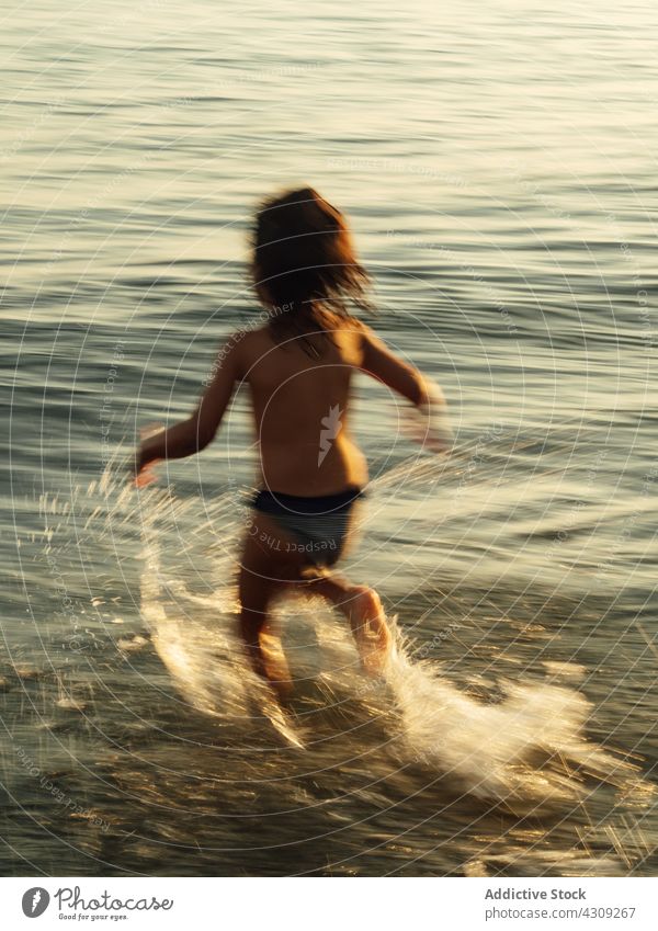 Happy kid running in sea water beach summer splash happy child having fun enjoy vacation childhood holiday ocean nature carefree little recreation summertime