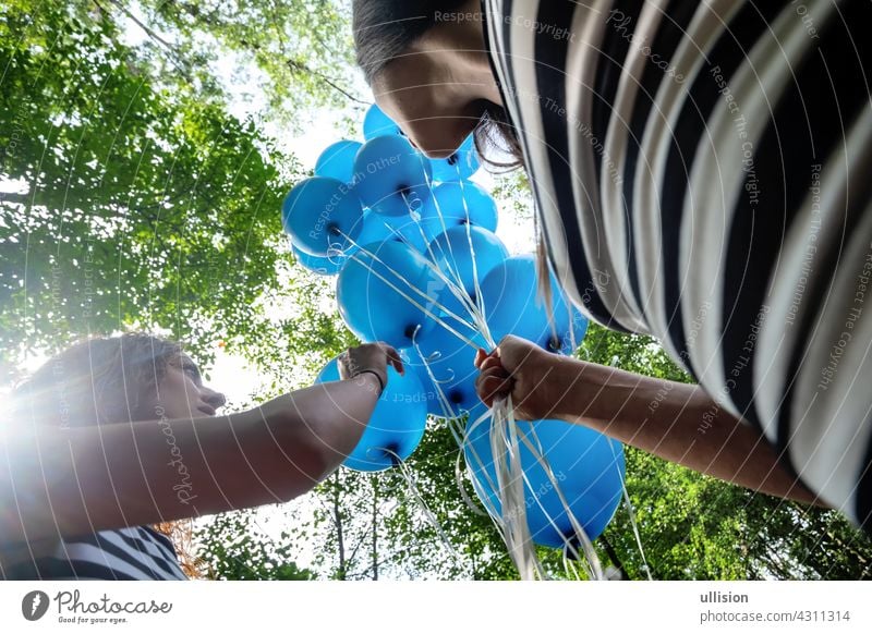 View from below on 2 blond women in black and white striped little ones with a bunch of blue balloons friends people fun beauty female adult fashion summer