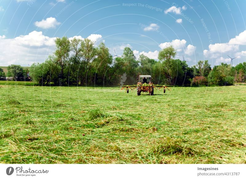 Agriculture - Mowing meadow. Red tractor mowing green pasture. Farmer in a modern tractor on a sunny day. agricultural field Machinery Clouds country Landscape