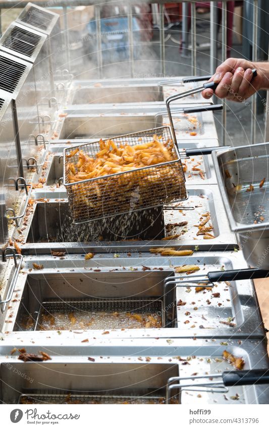 fresh fries are taken out of a deep fryer at a festival French fries preparation celebrations Potatoes Marketplace Fat Delicious Nutrition Food Eating Snack bar