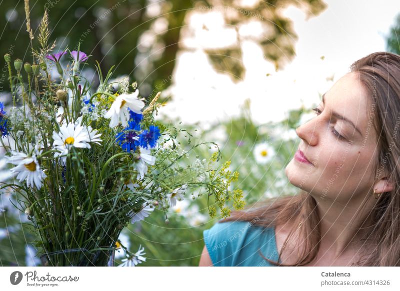 The young woman holds a bouquet of meadow flowers, in the background a flower meadow Nature flora person feminine Young woman Brunette naïve look Plant Blossom