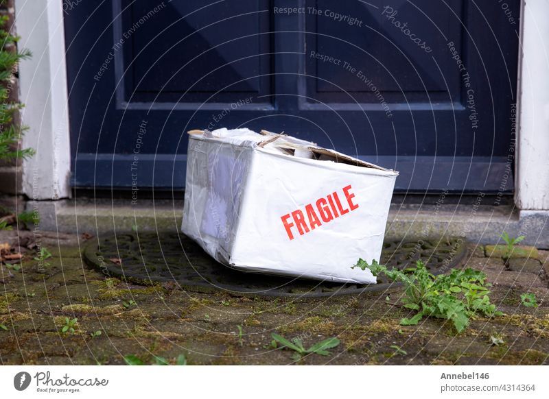 Damaged delivery cardboard box at front door of a house, Fragile package with dents, bad delivery concept fragile shipping parcel damaged care container