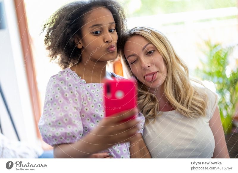 Mother and her young daughter taking a selfie at home mother child family multi-ethnic mixed race family diverse family diversity afro real people millennial