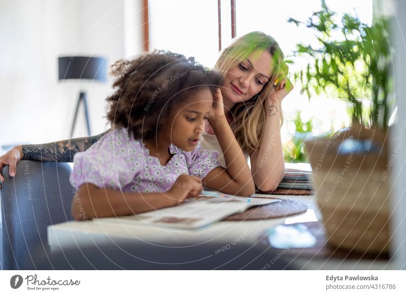 Mother helping daughter with homework mother child family multi-ethnic mixed race family diverse family diversity afro real people millennial hair girl children