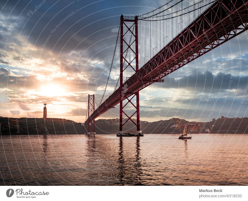 Ponte 25 de Abril Bridge in Lisbon during Sunset with ship and jesus monument, cloudy sky portugal ponte 25 de abril sunset lisbon bridge river city