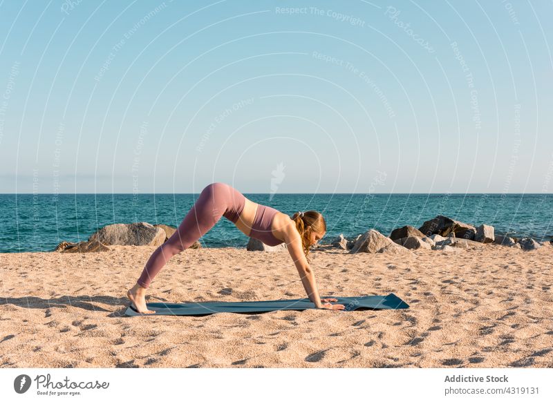 Woman doing yoga in Downward Facing Dog pose on beach woman practice harmony downward facing dog pose stretch flexible asana sea female sand healthy position
