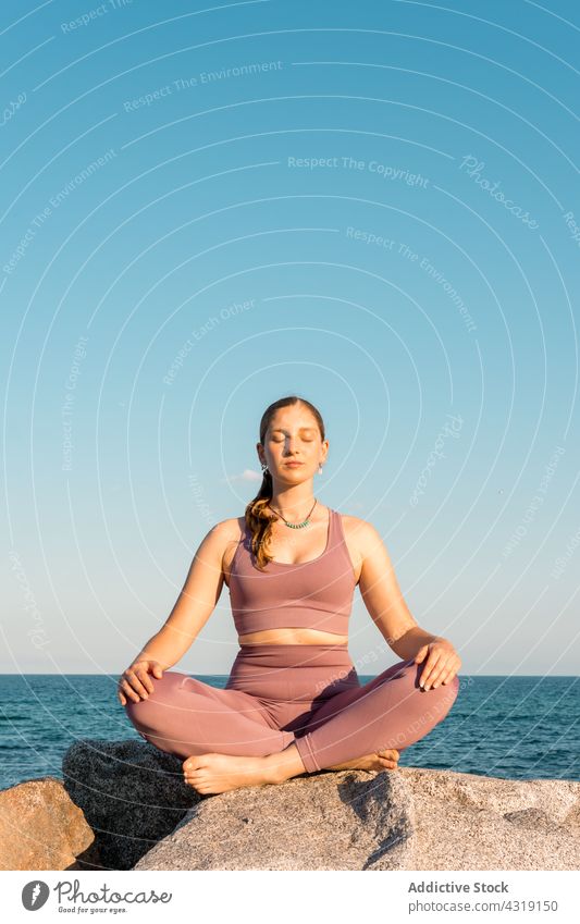 Woman practicing yoga in Lotus pose on beach woman meditate lotus pose asana zen practice mindfulness female healthy shore balance padmasana calm relax wellness