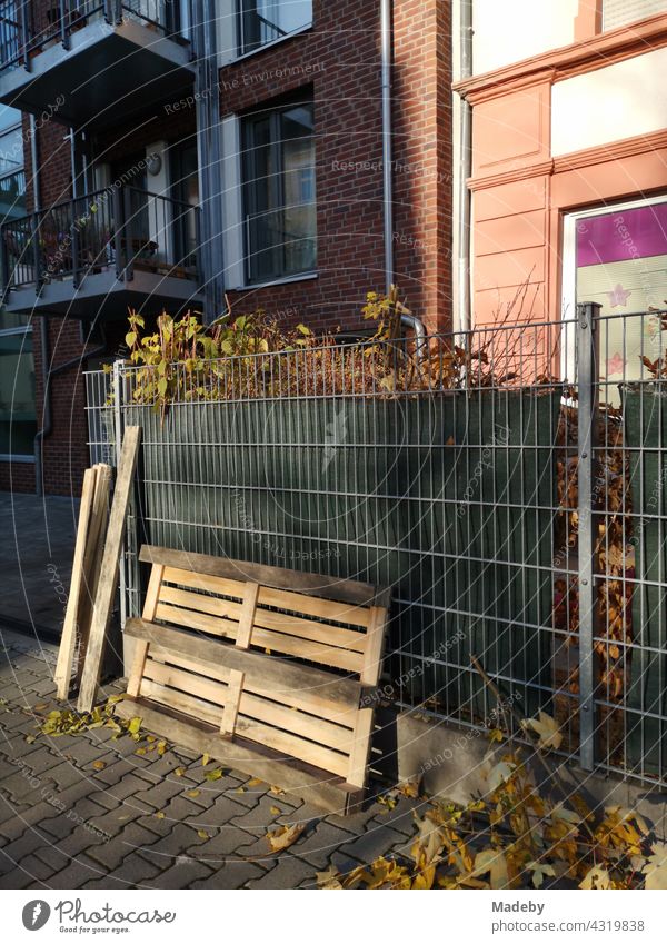 Old wooden pallet in the sunshine in front of a wire fence on the sidewalk in the Westend of Frankfurt am Main in Hesse, Germany Wood Euro Pallet Transport