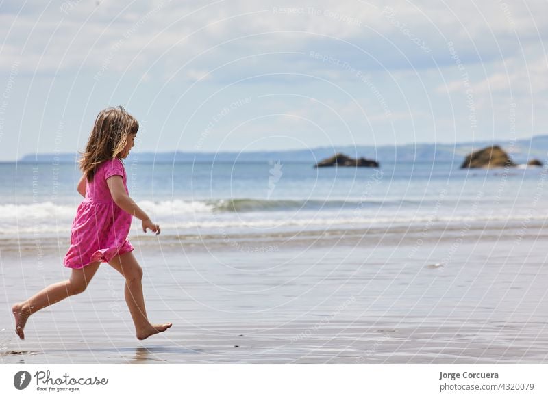 girl running on the beach with a clear horizon and great copy space sand playing adorable toddler kid summer young child childhood sea person cute caucasian